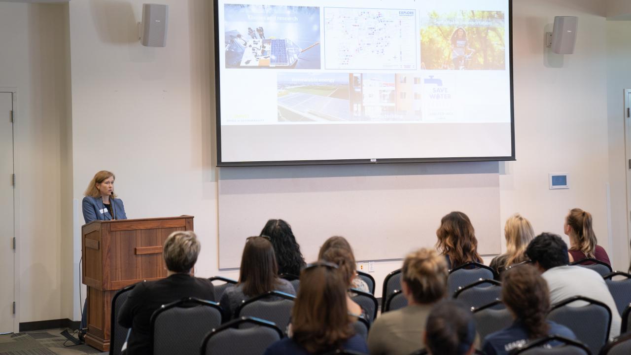 Camille Kirk speaks from a podium in front of a crowd of UC Davis students