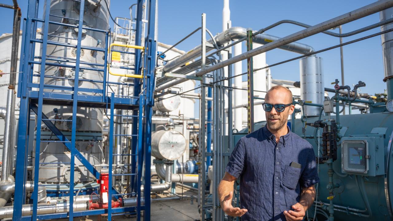 Man stands among pipes, tanks and other equipment