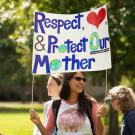 Person holds a sign that reads "Respect & Protect Our Mother"